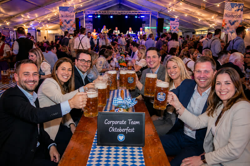 Corporate team raising beer glasses at a reserved table